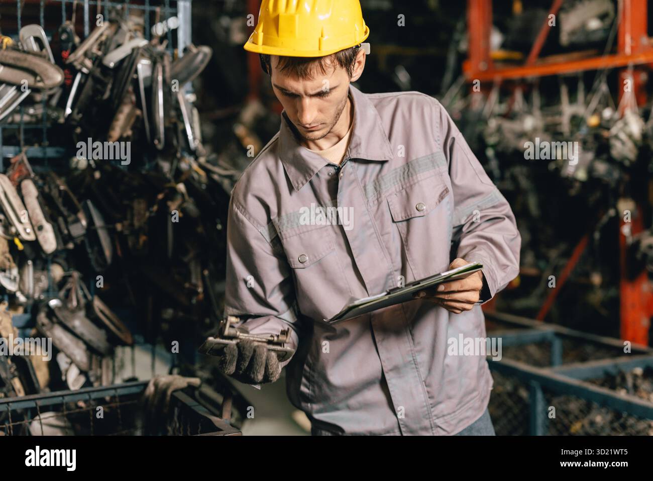 Techniker männliche Arbeiter prüfen den Bestand im Lager alter Gebrauchtmaschinenteile mit Schutzhelm. Stockfoto
