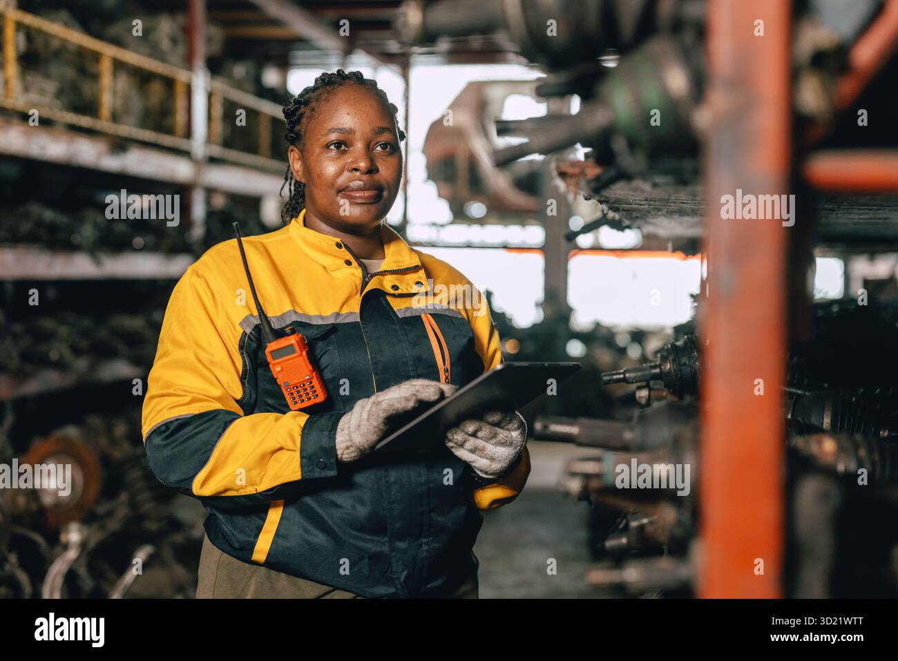 Glückliche schwarze afrikanische Ingenieurinnen arbeiten gerne in alten Lagerlagern für gebrauchte Metallmaschinenteile. Stockfoto