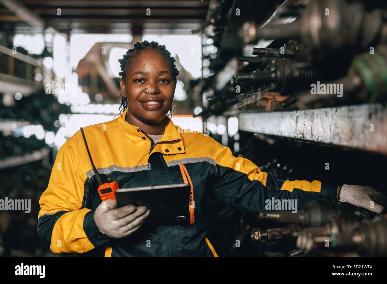 Glückliche schwarze afrikanische Ingenieurinnen arbeiten gerne in alten Lagerlagern für gebrauchte Metallmaschinenteile. Stockfoto