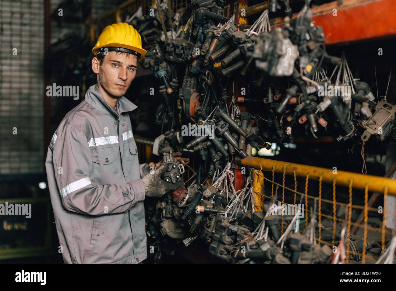 Techniker männliche Arbeiter prüfen den Bestand im Lager alter Gebrauchtmaschinenteile mit Schutzhelm. Stockfoto