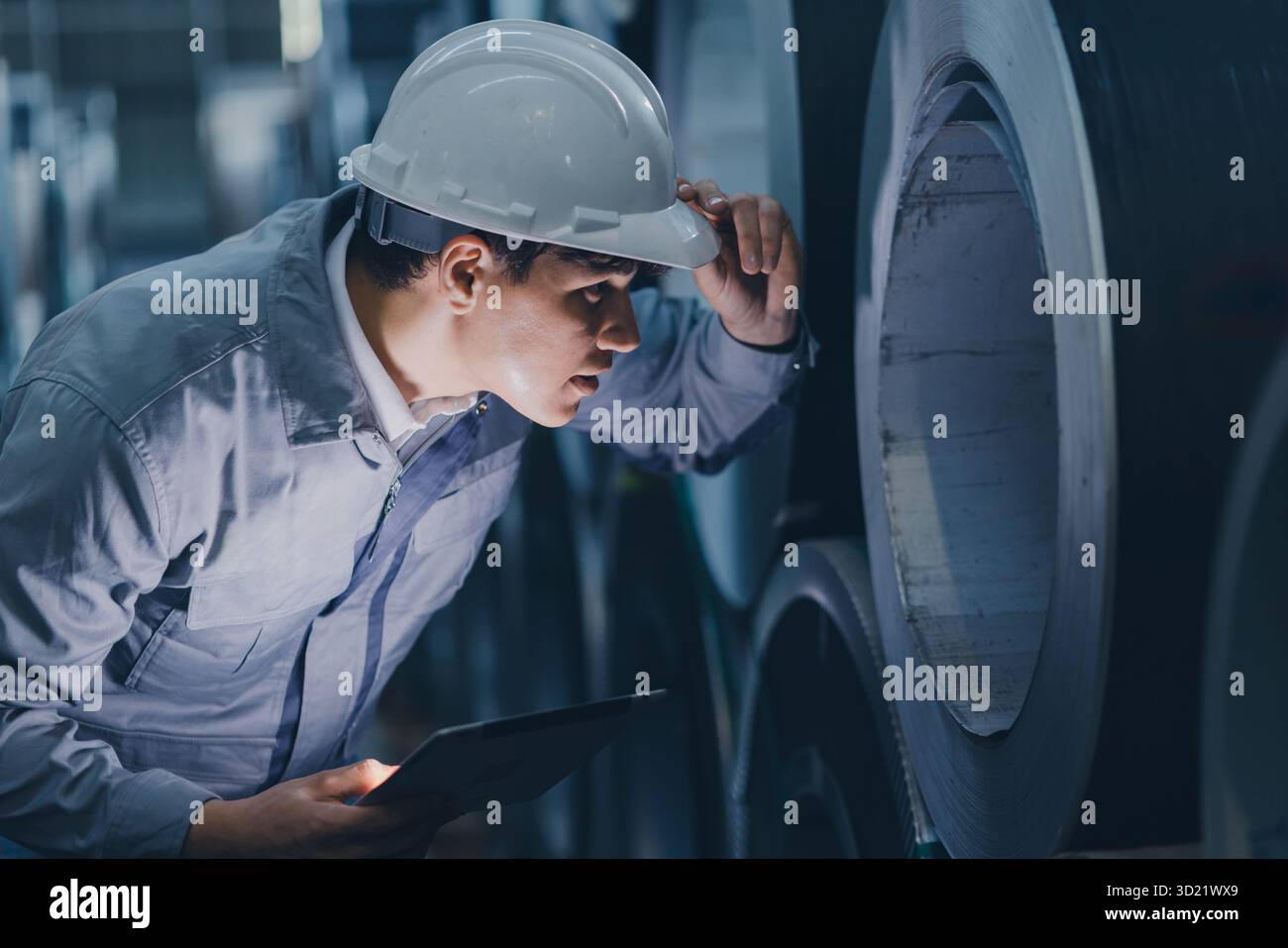 Professioneller Ingenieur, der in der Schwermetallindustrie arbeitet und Blechwalzen mit Sorgfalt und großer Erfahrung überprüft Stockfoto