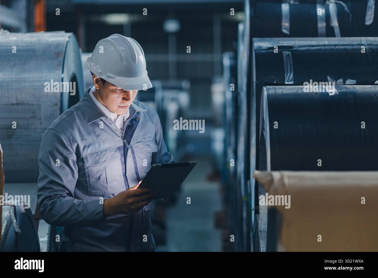 Professioneller Ingenieur, der in der Schwermetallindustrie arbeitet und Blechwalzen mit Sorgfalt und großer Erfahrung überprüft Stockfoto