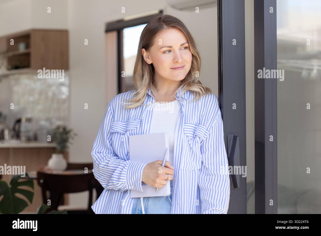 Entschlossene blonde Frau hält Notizbuch und Stift im Büro Stockfoto