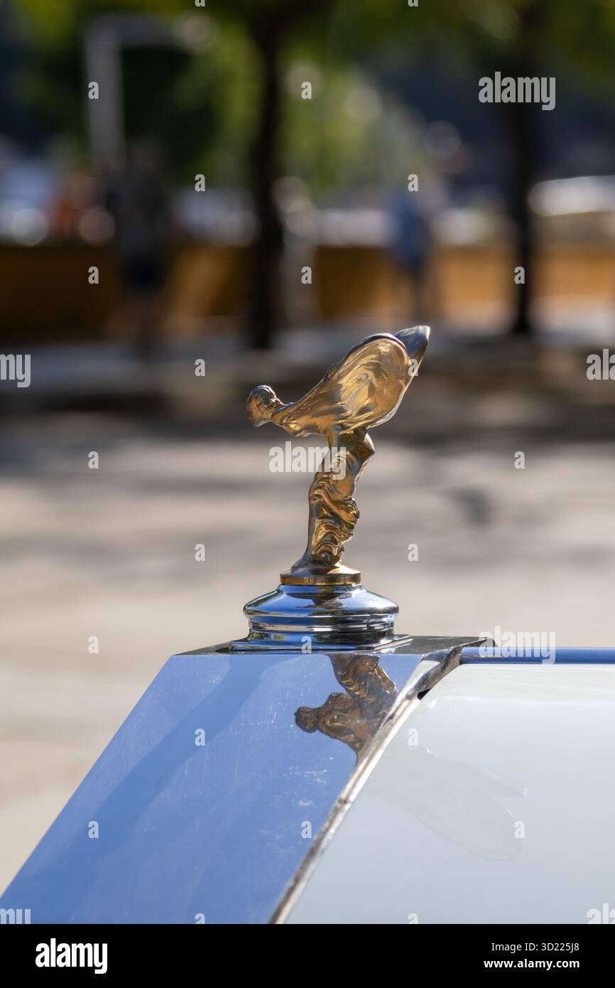 Die Figur „Spirit of Ecstasy“ ziert die Motorhaube eines Oldtimer-Luxusautos und das goldfarbene Emblem reflektiert das Licht Stockfoto