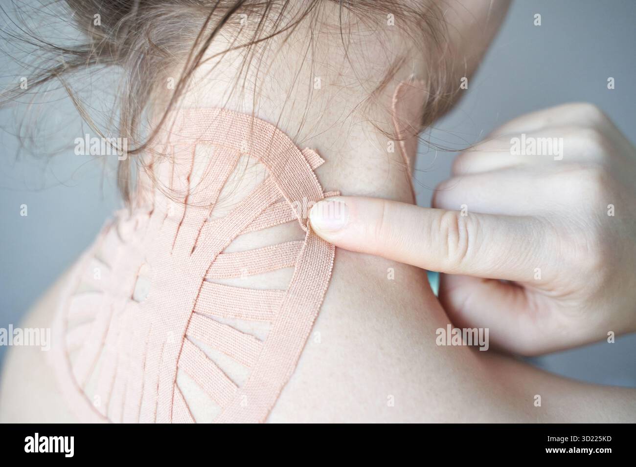 Weibliche Anwendung von therapeutischem Kinesiologieband am Hals zur Schmerzlinderung und Muskulatur Stockfoto