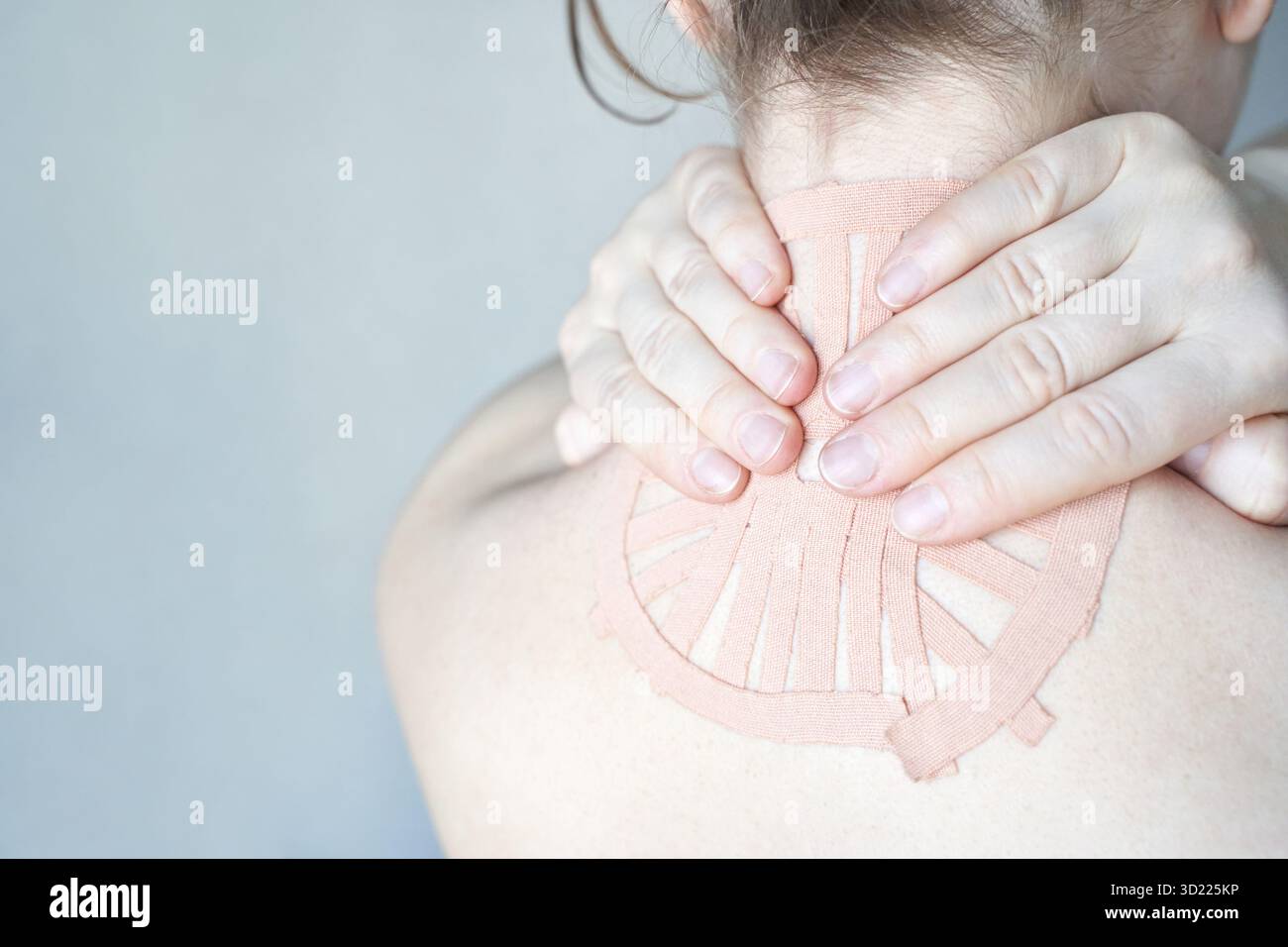 Kaukasische Erwachsene Erwachsene mit Kinesiologieband am Nacken zur Schmerzlinderung Stockfoto