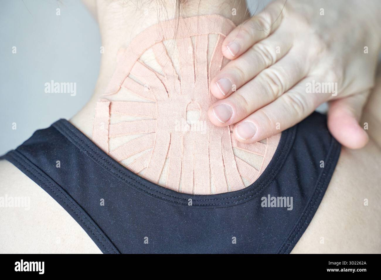 Kaukasische Frau, die Kinesiologieband am Hals zur Schmerzlinderung und Muskulatur anbringt Stockfoto