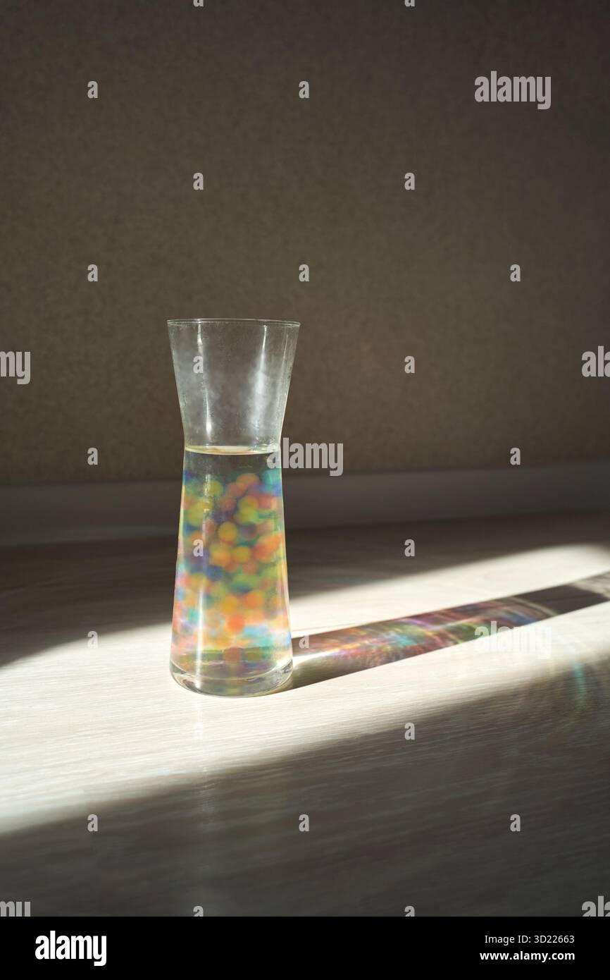 Bunte Lichtbrechung durch eine Glasvase mit Wasserperlen bei Sonnenlicht Stockfoto