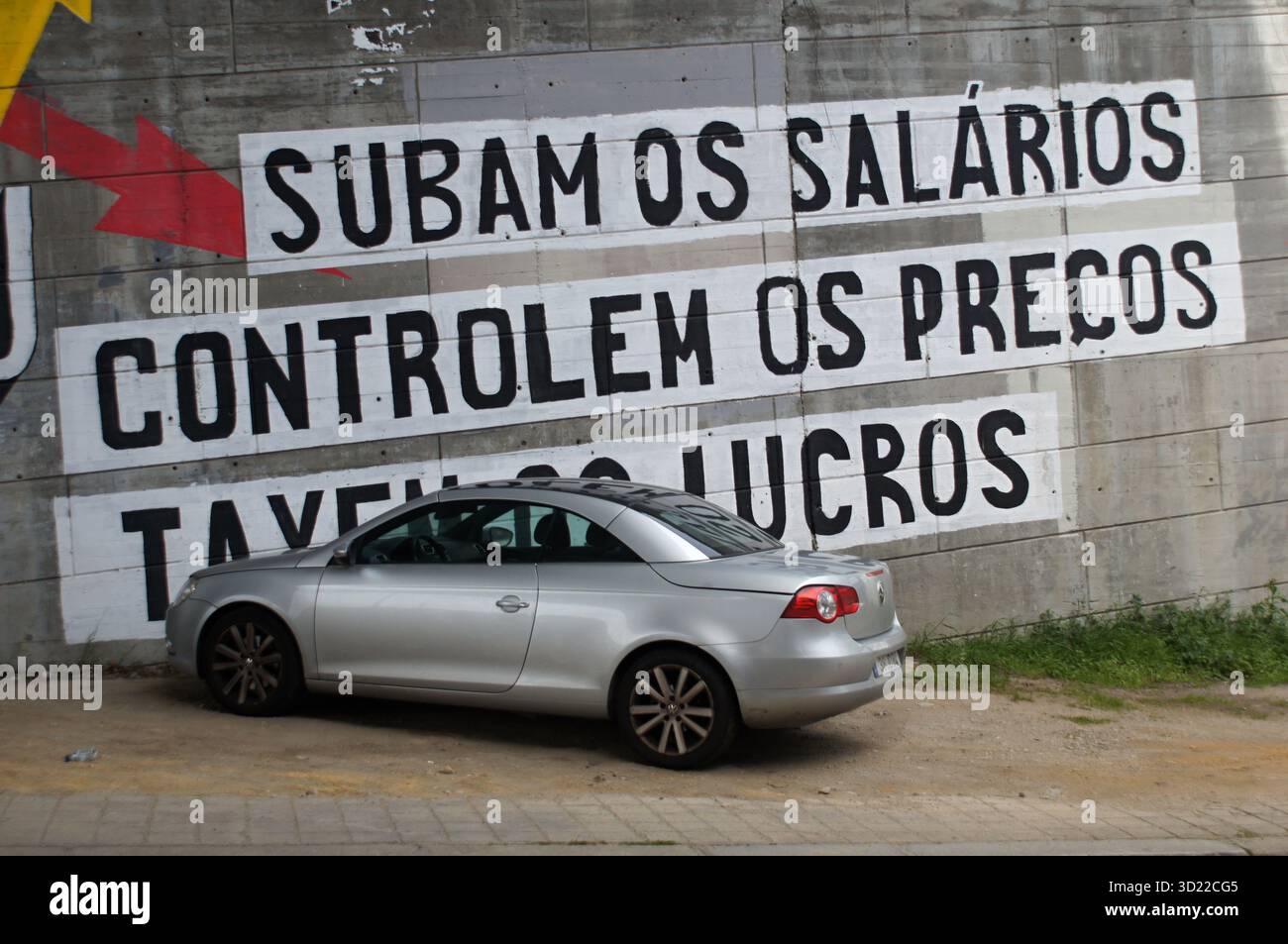Geparktes silbernes Cabriolet neben Graffiti in portugiesischer Sprache, das nach Gehaltserhöhung, Preiskontrolle und Gewinnbesteuerung fragt Stockfoto