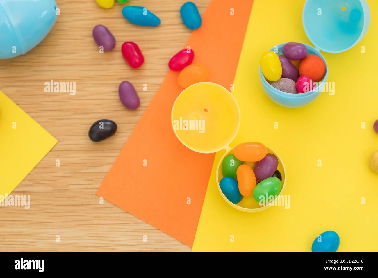 Heller Hintergrund mit Süßigkeiten in Form von Ostereiern in Plastikeiern. Das Konzept der Eierjagd. Frohe Ostern. Draufsicht. Stockfoto