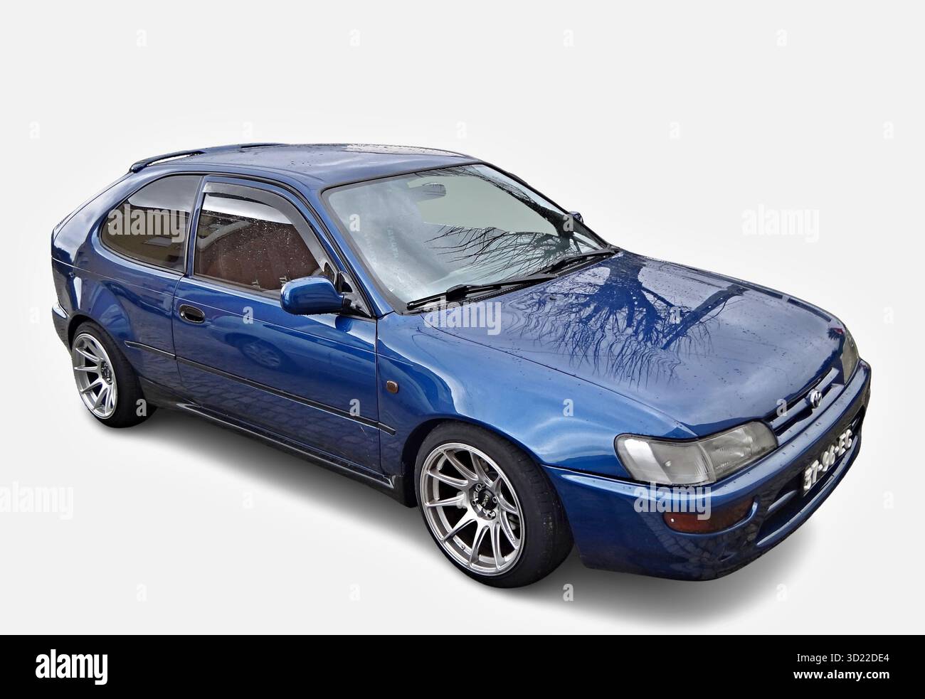 Der getunte Toyota Corolla E10 hebt seine Motorhaube an und zeigt Leichtmetallfelgen und Regenreflexion Stockfoto