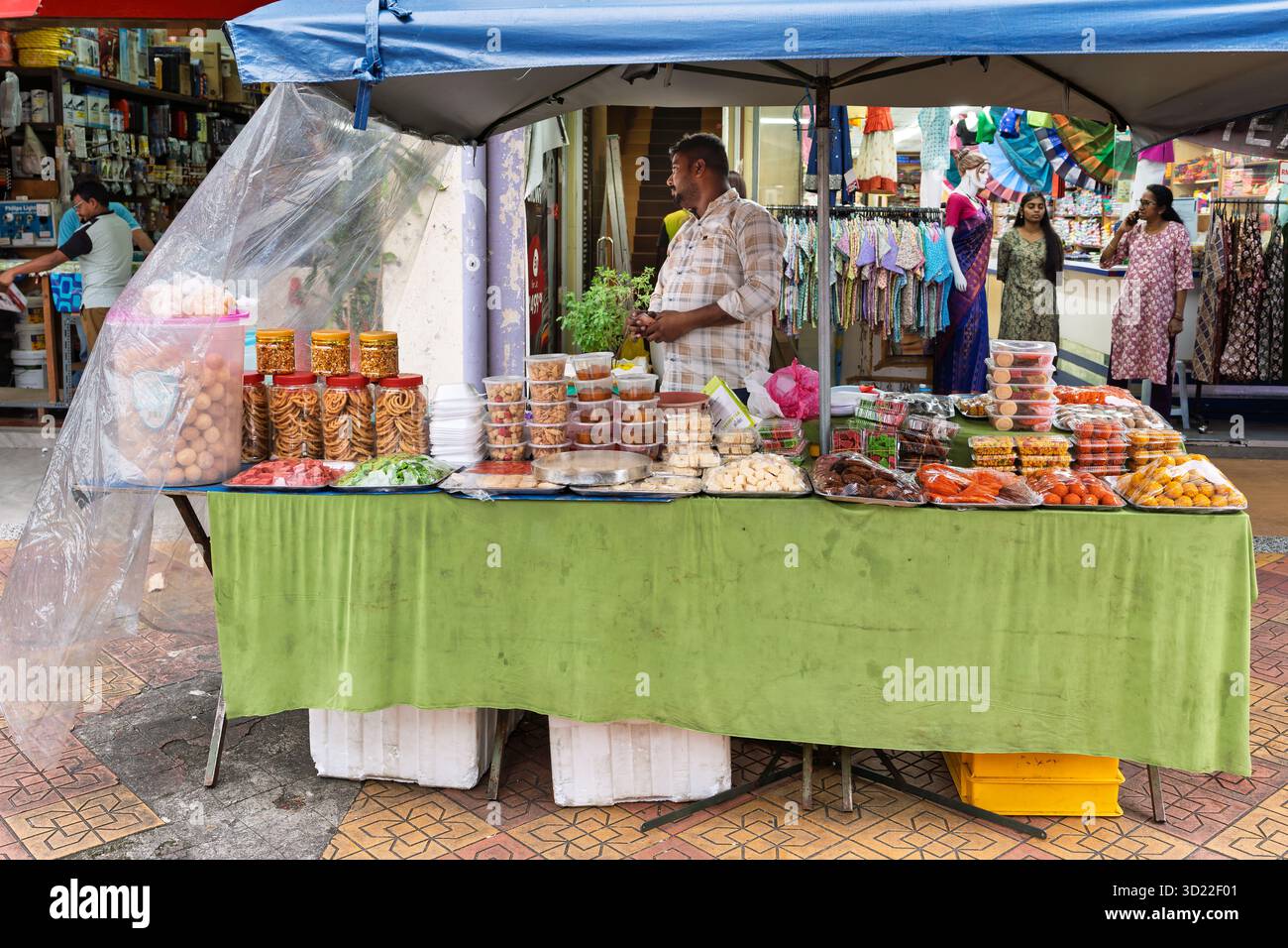 Straßenverkäufer, der traditionelle indische Köstlichkeiten an einem lebhaften Marktstand in Little India, Kuala Lumpur, Malaysia verkauft. Alltagsleben. Stockfoto