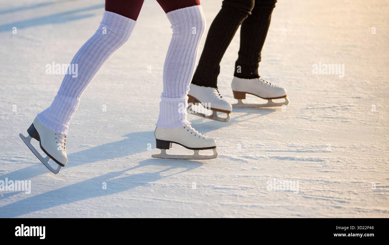 Nahaufnahme von Frauenbeinen auf Schlittschuhen im Winter auf offener Eislaufbahn. Winterzeit, Outdoor-Aktivitäten. Stockfoto