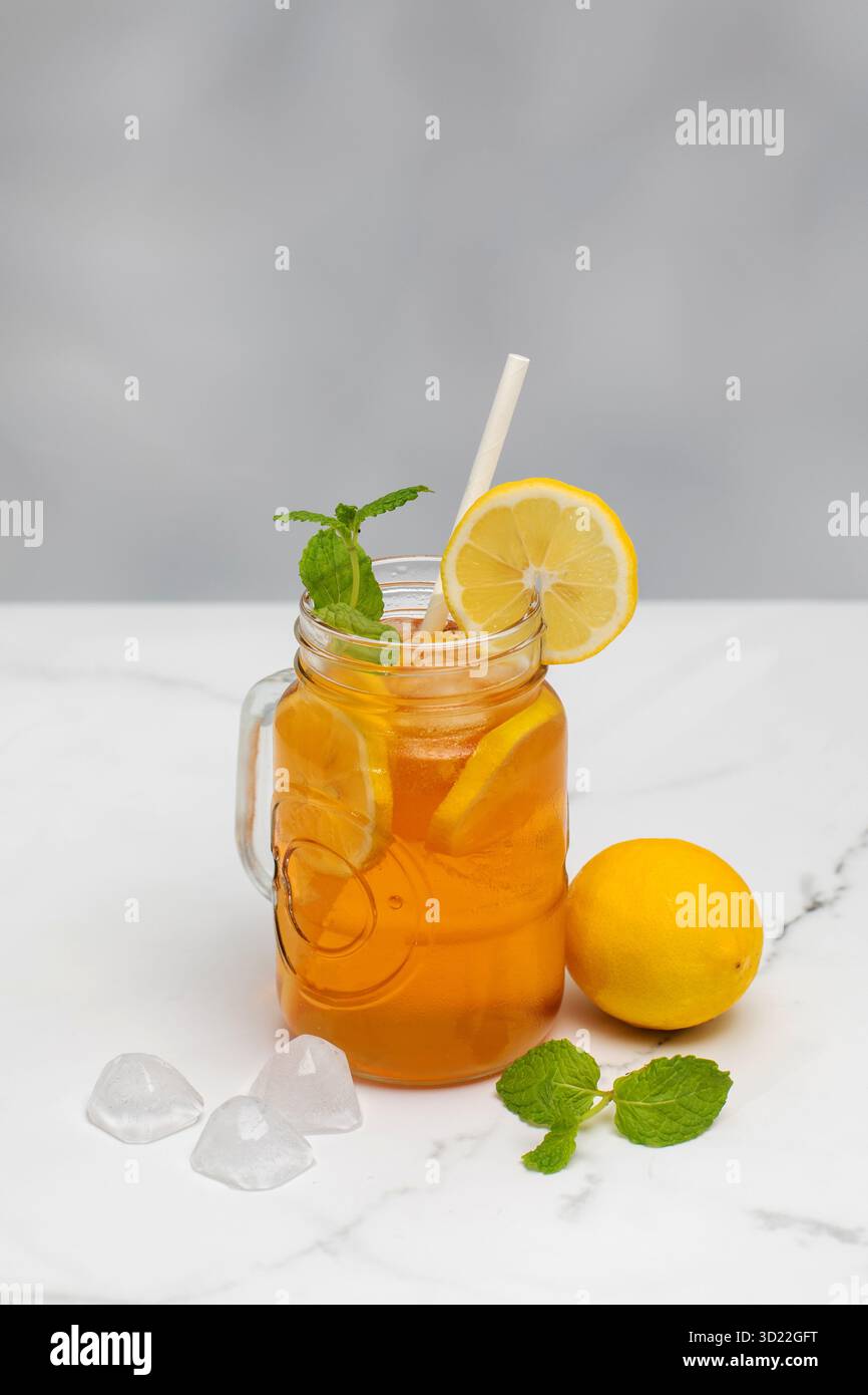 Ein Glas mit einem sommerlichen kühlen Getränk. Eistee mit Zitrone und Minze. Stockfoto