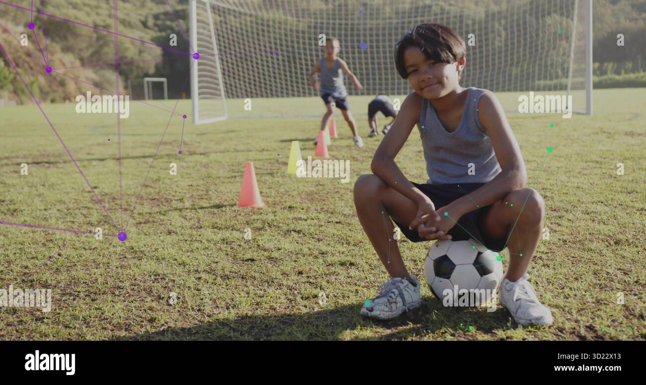 Squatting Boy in Sportswear Training auf dem Fußballfeld mit Trainingskegeln und Tornetz, Kopierraum Stockfoto