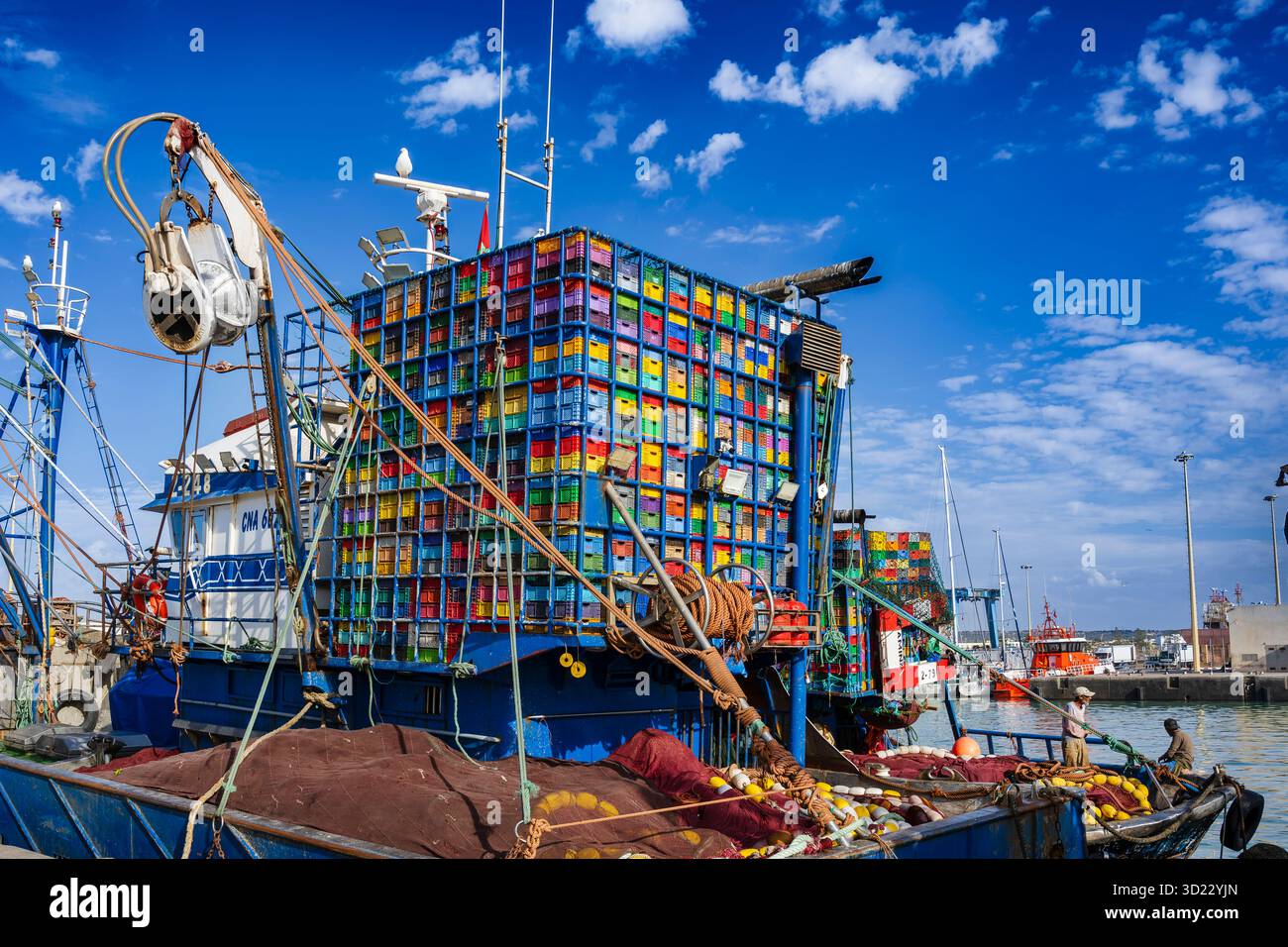Fischerboote mit bunten Kisten an einem geschäftigen Hafen unter klarem blauen Himmel. Essaouira, Marokko Stockfoto