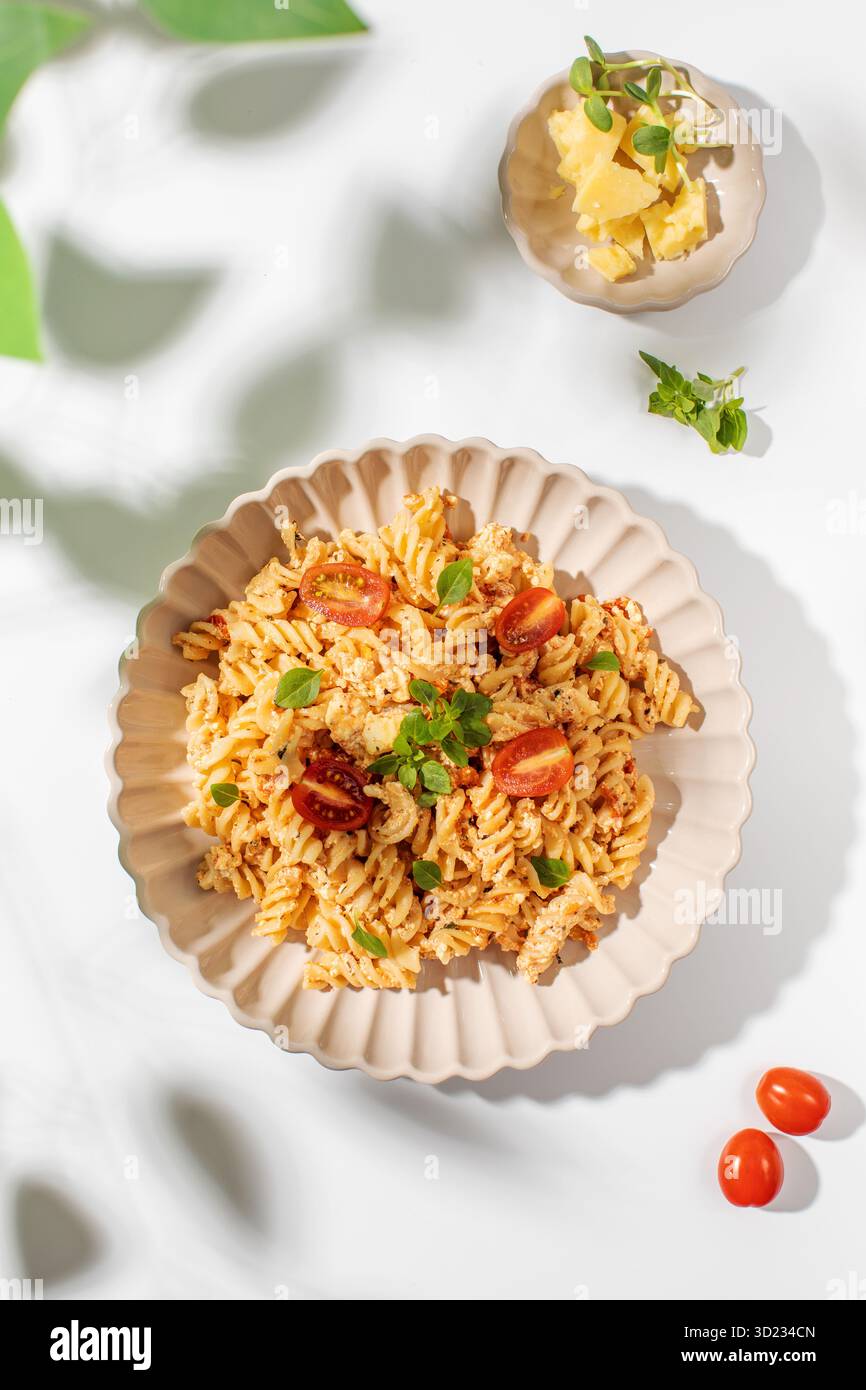 Teller Spiralnudeln mit Fetakäse und Kirschtomaten, garniert mit frischen Kräutern Stockfoto