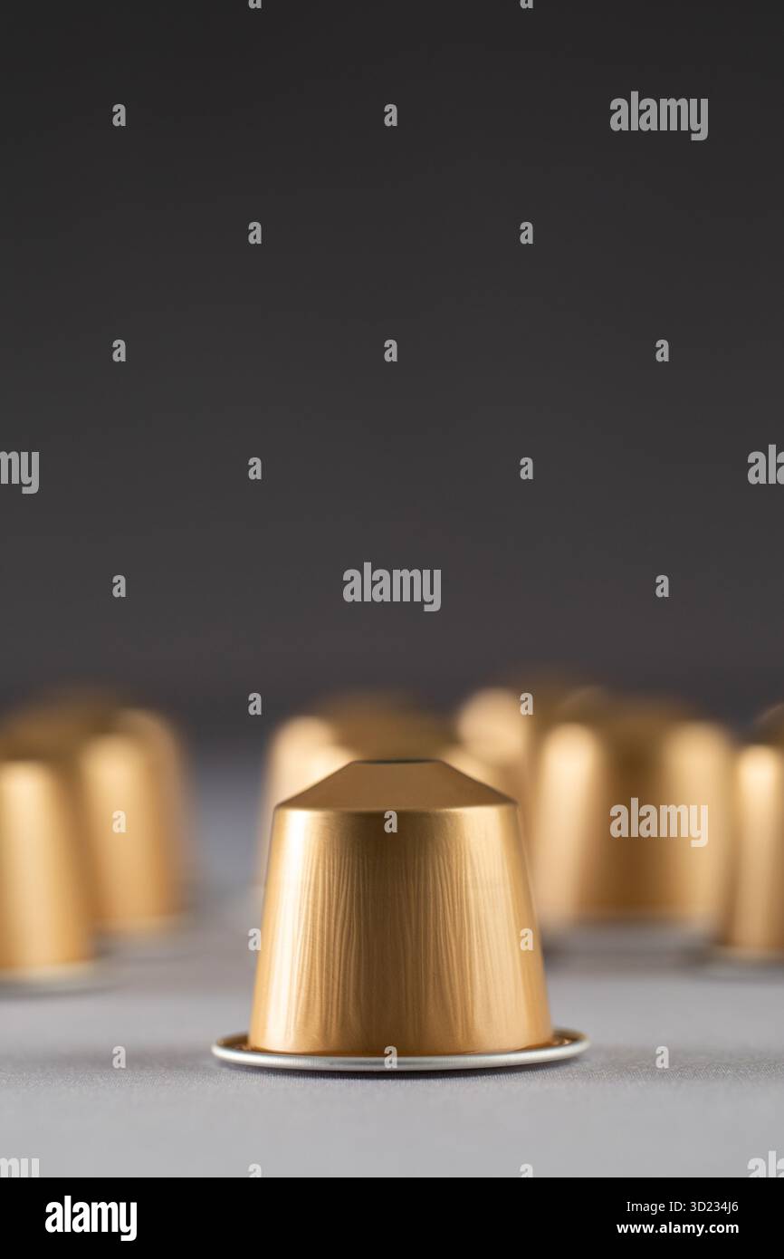 Goldene Kaffeekapseln auf neutralem Hintergrund, modernes Design. Werbung Stockfoto