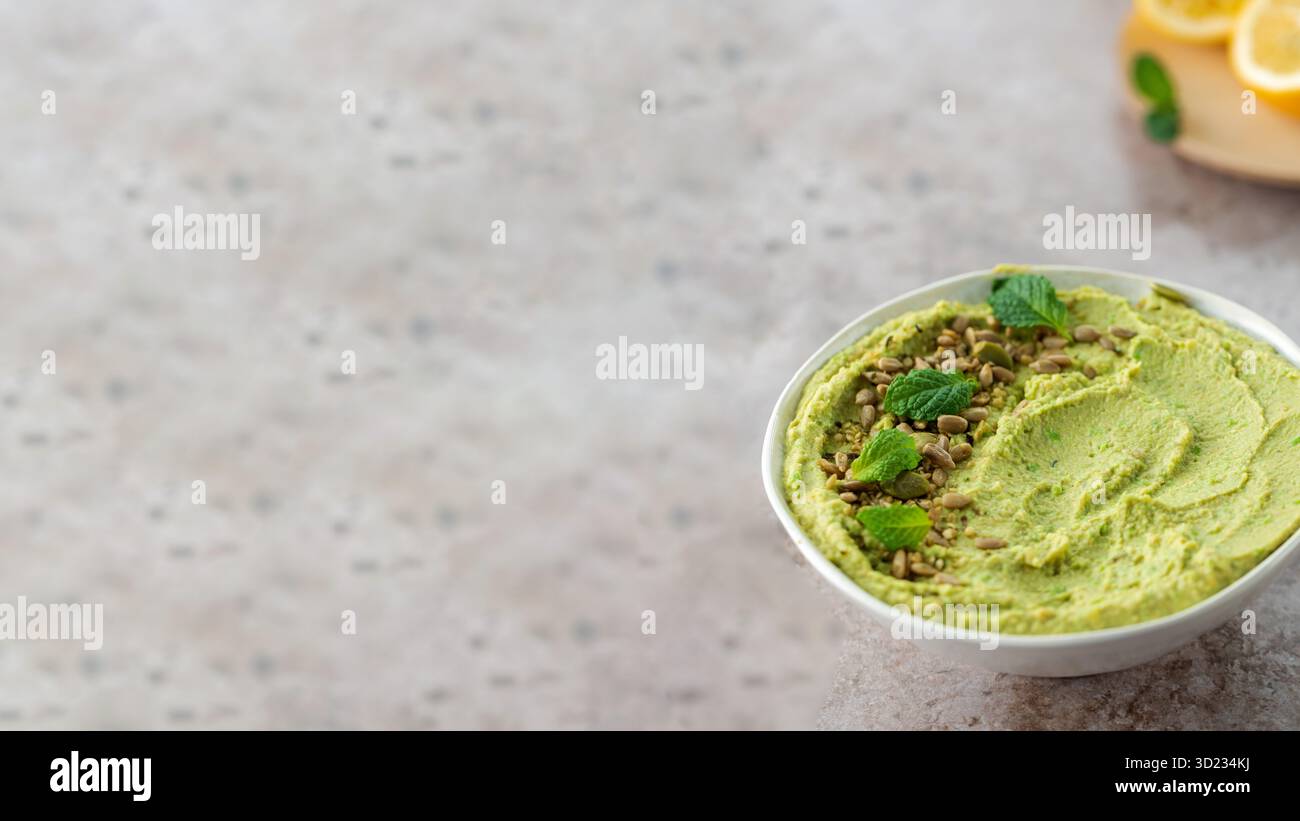 Hummus aus Kichererbsen, frischen grünen Erbsen und Minze, bestreut mit Samen. Kopierbereich Stockfoto