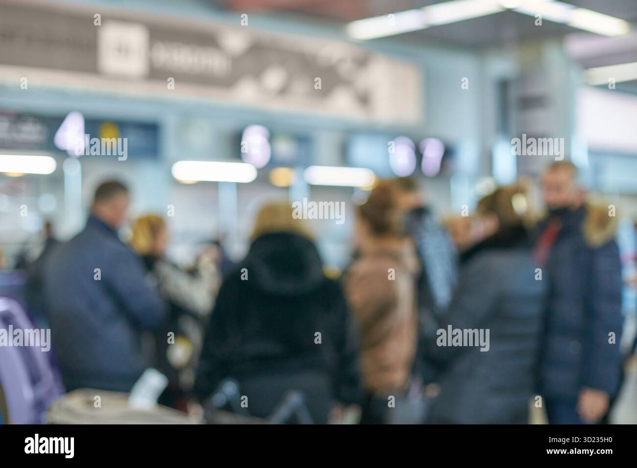 Verschwommenes Bild von verschiedenen Erwachsenen im geschäftigen Flughafen mit Schildern und Lichtern Stockfoto