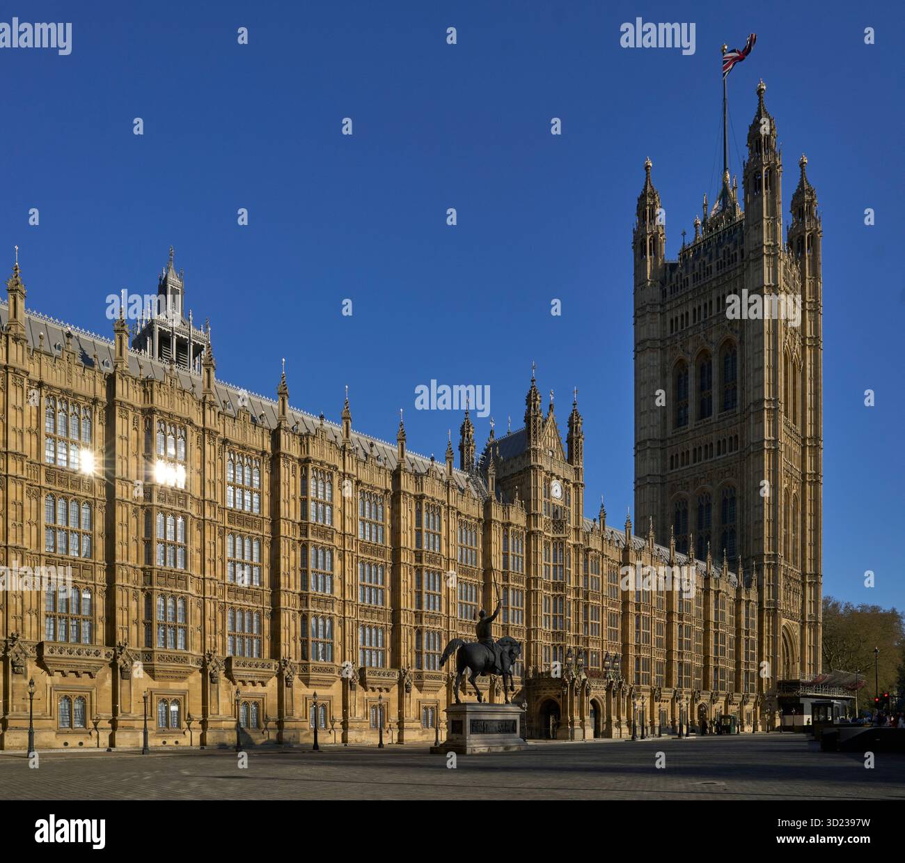 Old Palace Yard am Palace of Westminster, mit der Statue von Richard Löwenherz. Gebäude im gotischen Stil mit einem hohen Turm vor einem klaren blauen Himmel. London, Großbritannien Stockfoto