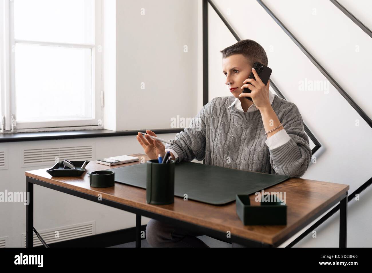 Reife Geschäftsfrau, die am Arbeitsplatz im Büro am Telefon spricht Stockfoto