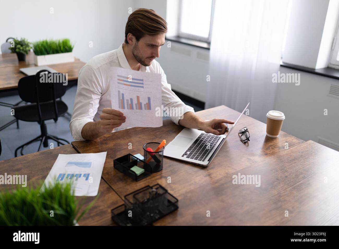 Geschäftsmann, der die finanziellen Angelegenheiten seines Unternehmens studiert und Diagramme in den Händen hält Stockfoto