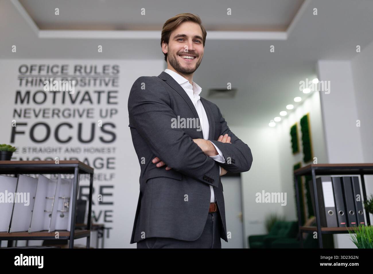 Ein erfolgreicher Geschäftsmann in einem Business-Anzug steht im Büro und sieht sich eine Superkamera an Stockfoto