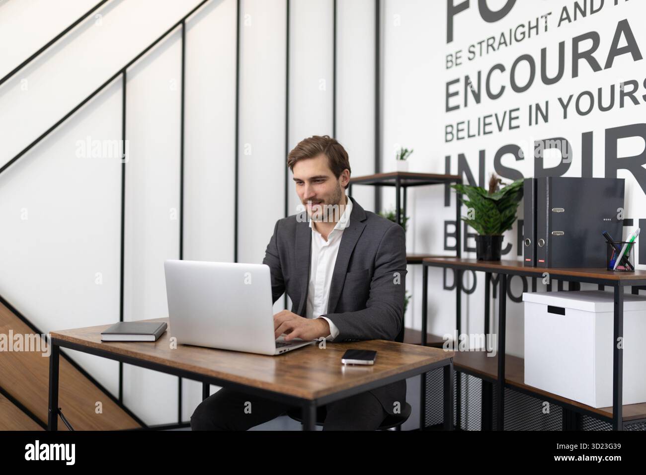 Ehrgeiziger junger erfolgreicher Geschäftsmann, der im Büro am Laptop arbeitet Stockfoto