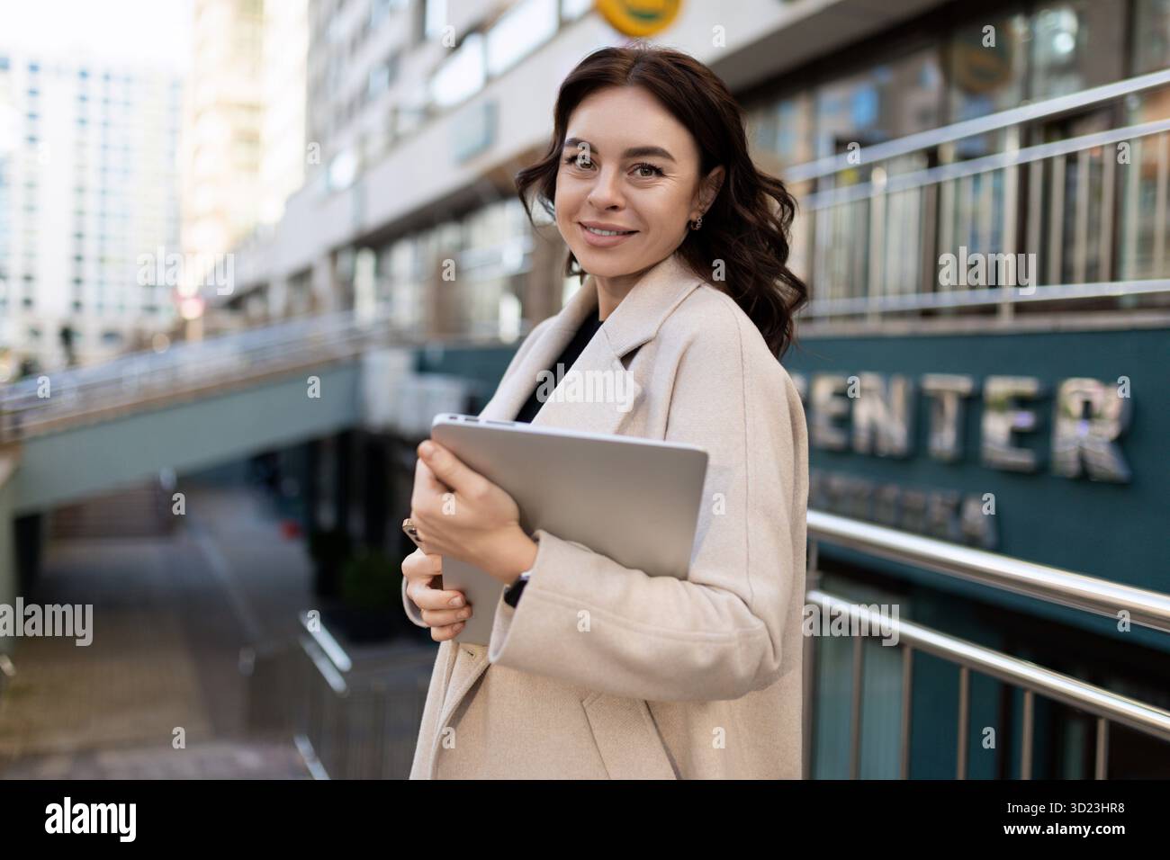Geschäftsfrau mit einem Laptop in der Hand auf dem Hintergrund der Stadt Stockfoto