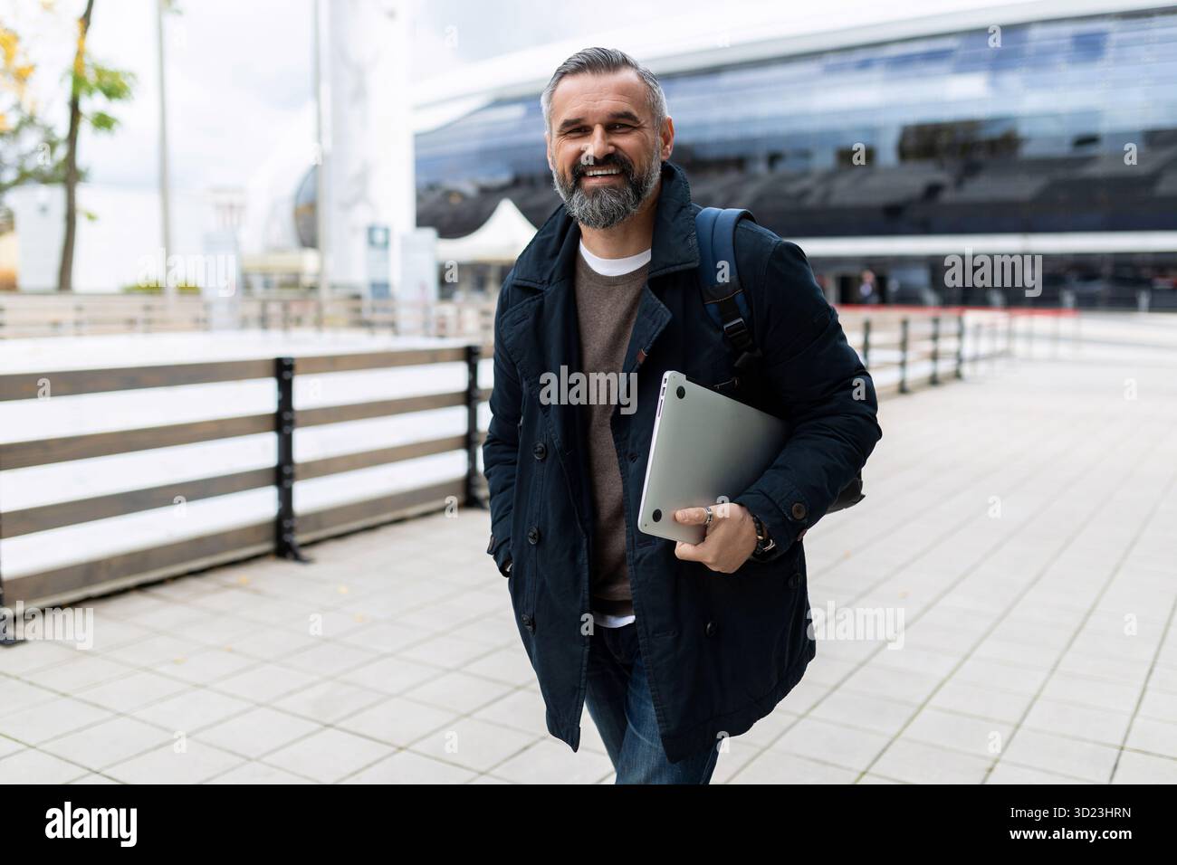 Reifer bärtiger Mann mit Laptop, der draußen läuft Stockfoto