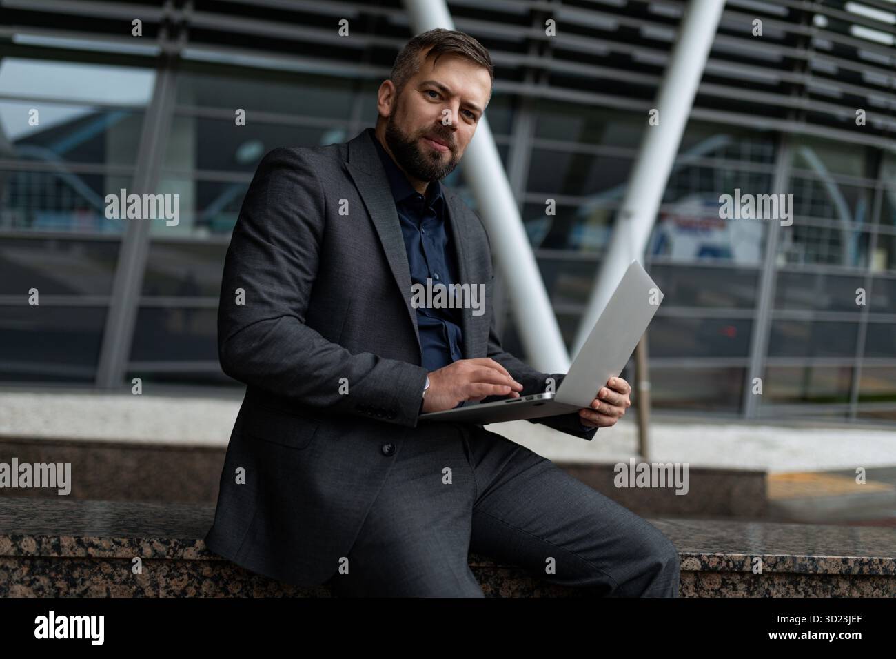 Geschäftsmann im Anzug mit Laptop vor dem Hintergrund eines Business Centers Stockfoto