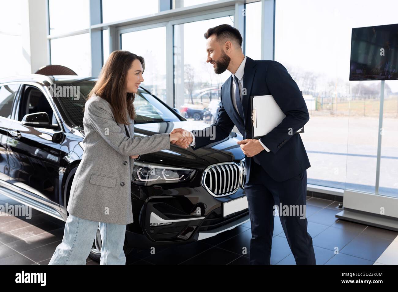 Manager und Käufer in einem Autohändler unterzeichnen Dokumente zum Kauf eines neuen Fahrzeugs Stockfoto