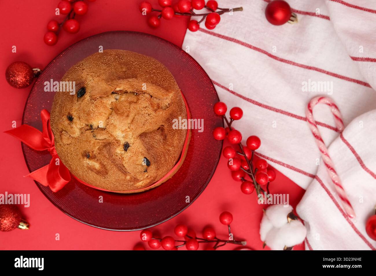 Teller mit leckerem Panettone und Weihnachtsdekor auf rotem Hintergrund Stockfoto
