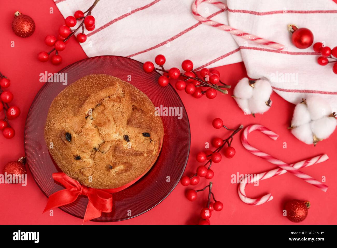 Teller mit leckerem Panettone und Weihnachtsdekor auf rotem Hintergrund Stockfoto