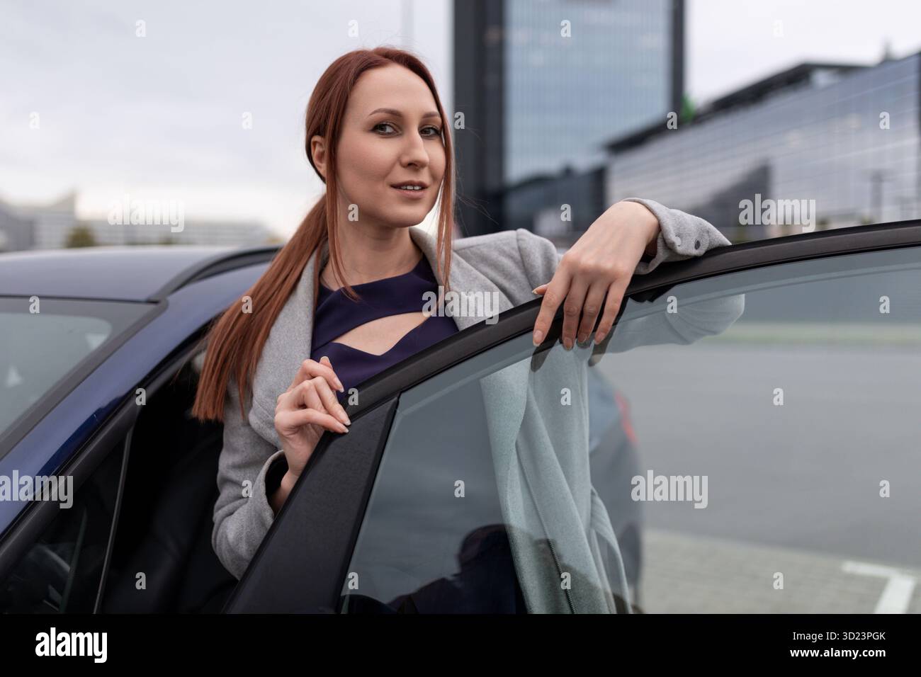 Geschäftsfrau, die vor dem Hintergrund eines Bürogebäudes aus dem Auto steigt Stockfoto