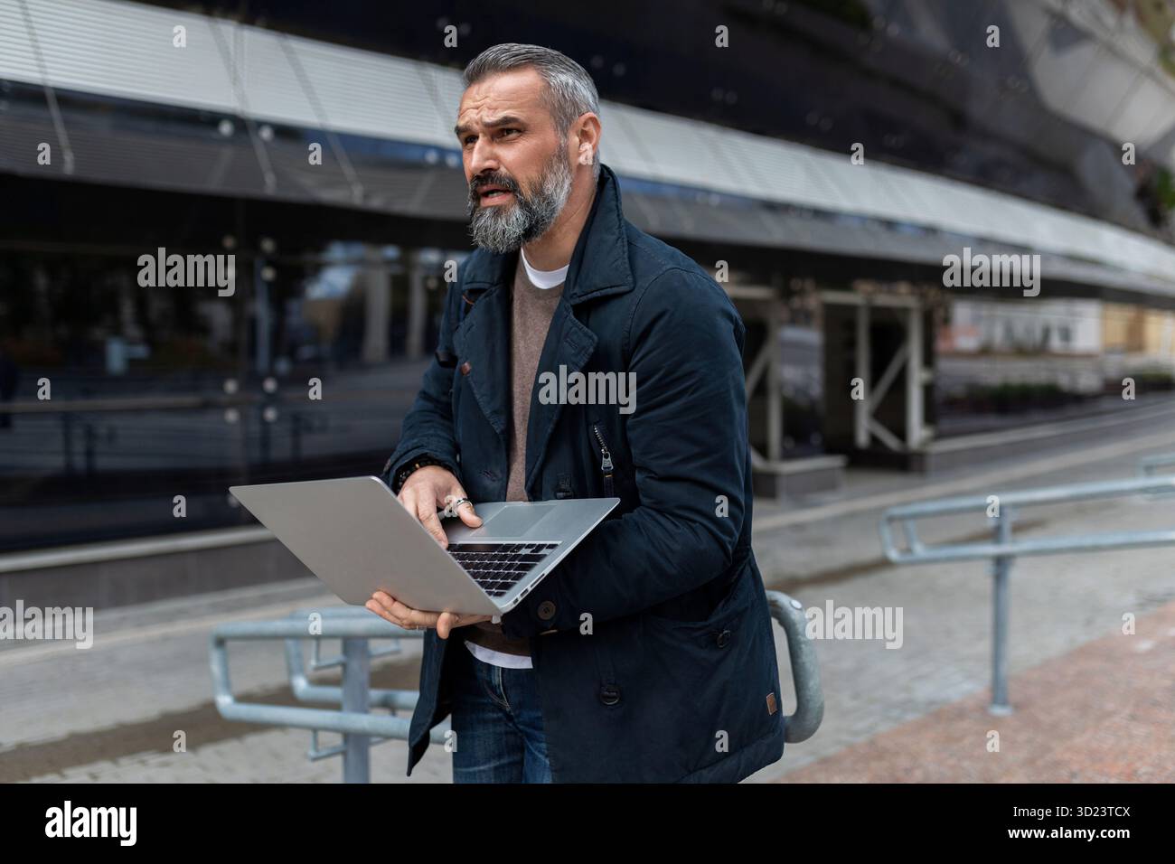 Software-Ingenieurin für Erwachsene mit einem Laptop in der Hand vor dem Hintergrund eines Business Centers im Büro Stockfoto