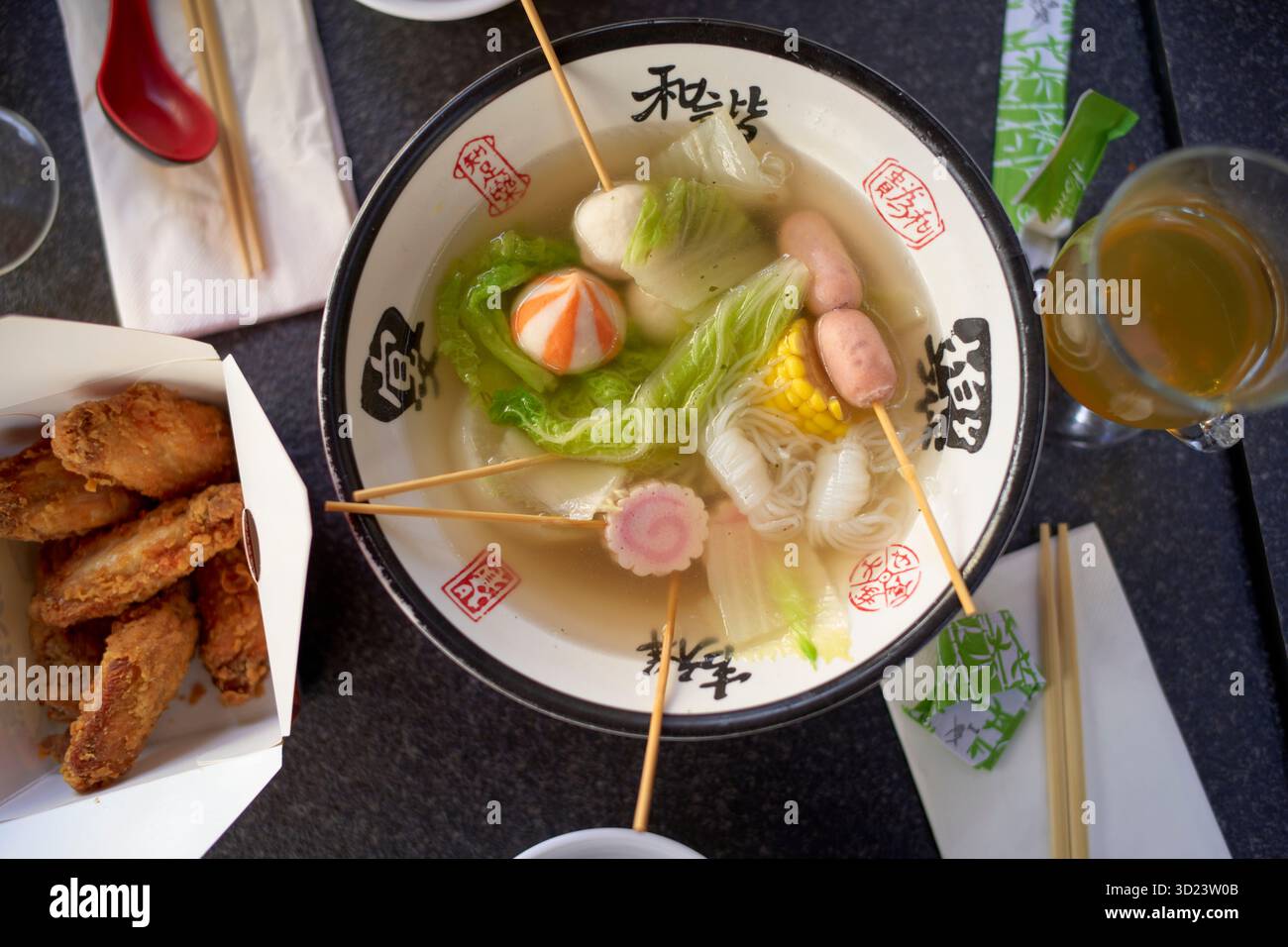 Asiatischer Topf mit Gemüse, Nudeln und Aufschnitt in einer dekorativen Schüssel, umgeben von Beilagen. Brüssel, Belgien Stockfoto