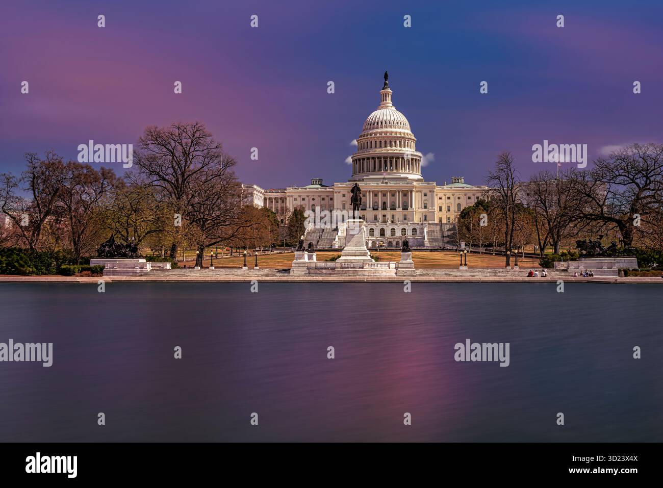 Das US Capitol in der Abenddämmerung mit einem lebendigen Himmel und ruhigem, reflektierendem Wasser im Vordergrund. WASHINGTON DC, WA, USA Stockfoto