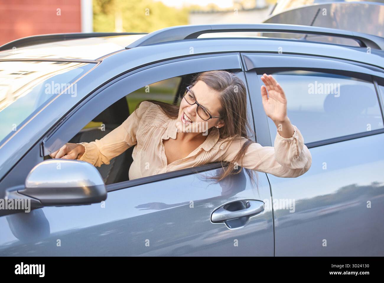 Kaukasische erwachsene Fahrerin in lässiger Kleidung bei hellem Sonnenlicht Stockfoto