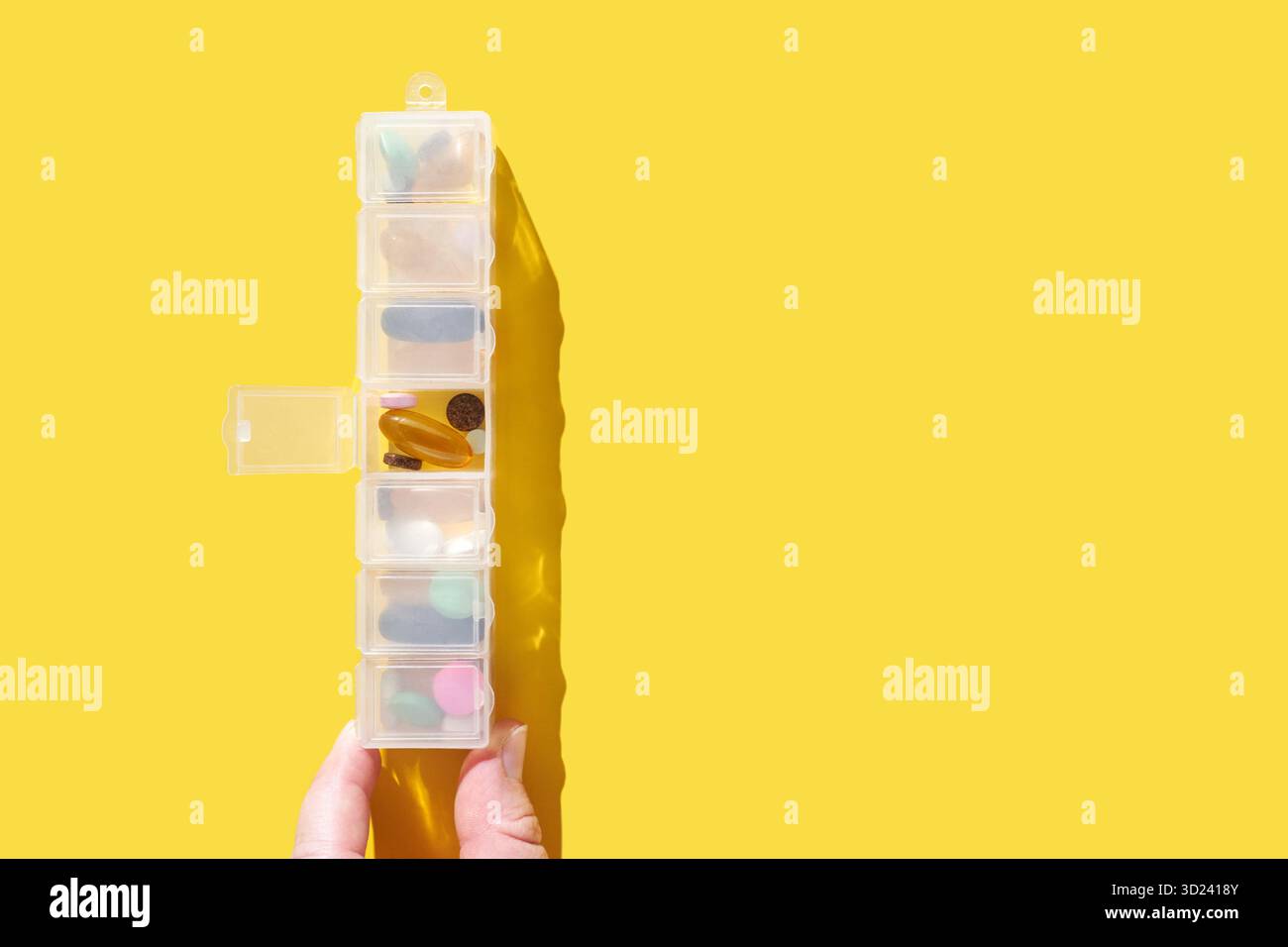 Hand halten transparente Pille Organizer mit verschiedenen Ergänzungen auf Bright Stockfoto