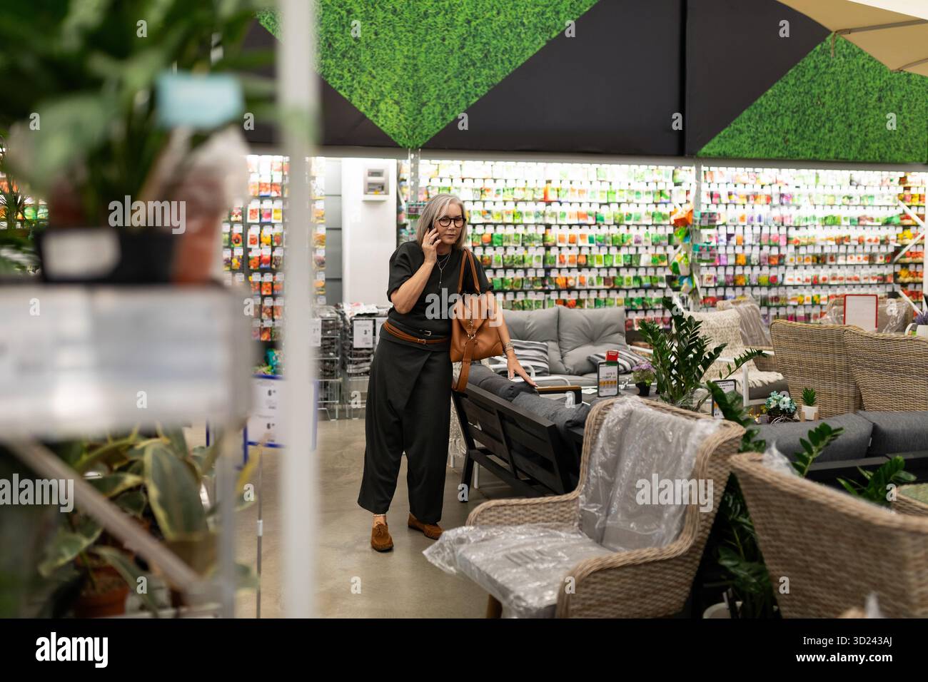 Kaufen Sie tagsüber in einem Garten- und Möbelgeschäft ein, während Sie ihr Gesicht nachdenklich berühren Stockfoto