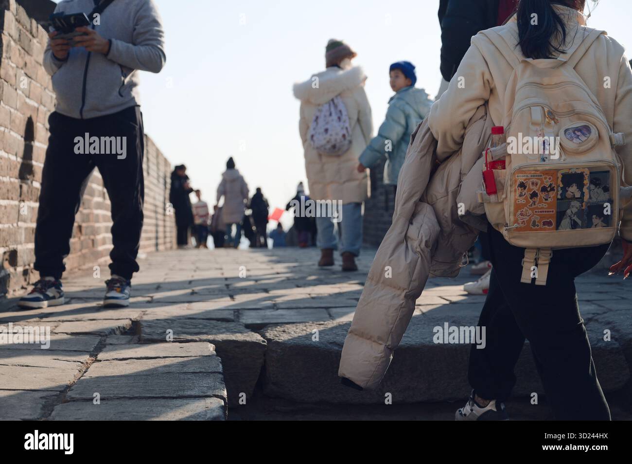 Besucher spazieren im Winter auf dem unebenen Steinweg der Chinesischen Mauer Stockfoto