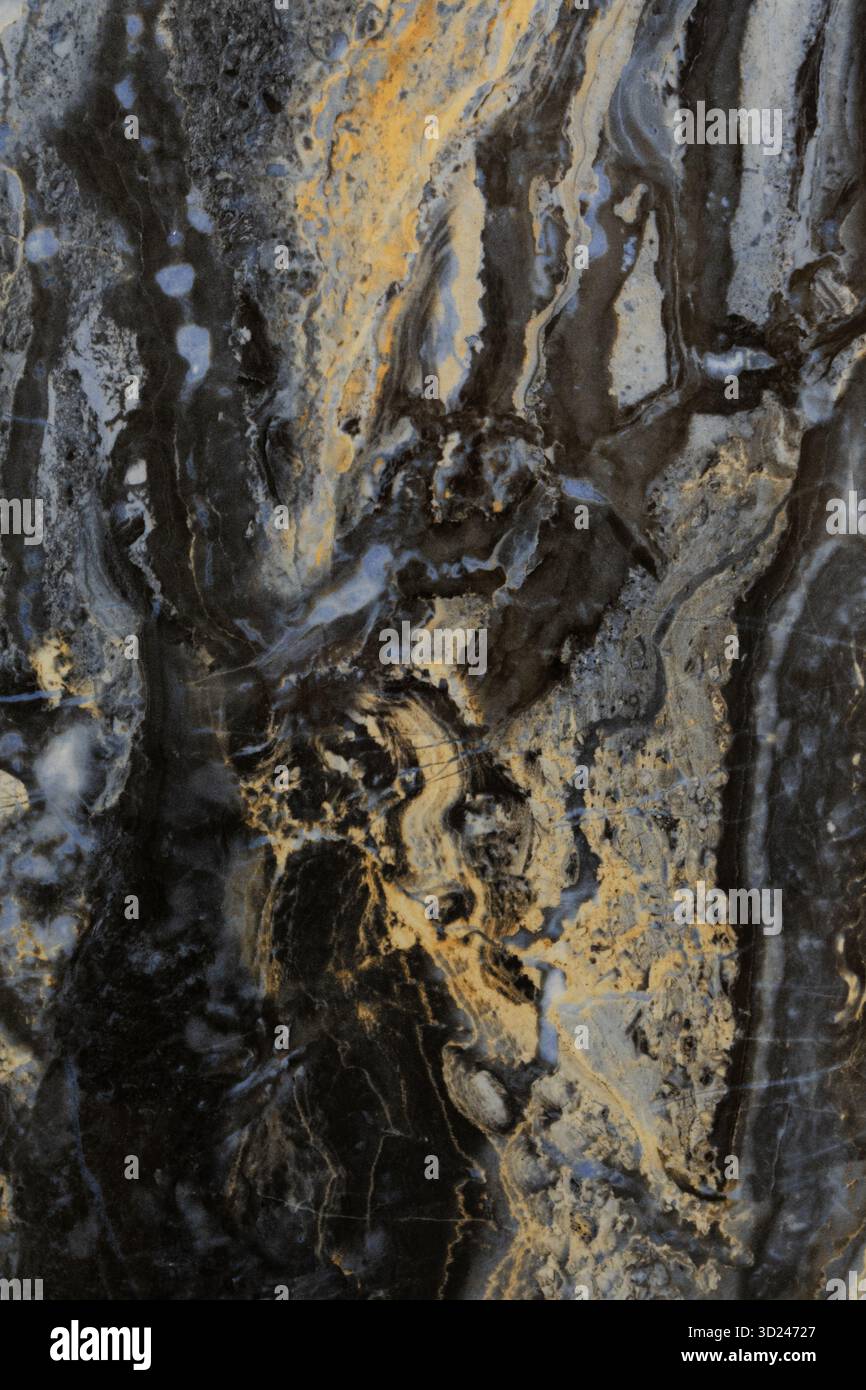 Dunkle Steinoberfläche mit einzigartigen wirbelnden Mustern und Farbtönen von Gold, Grau und Schwarz, die durch natürliche Mineralformationen erzeugt werden Stockfoto