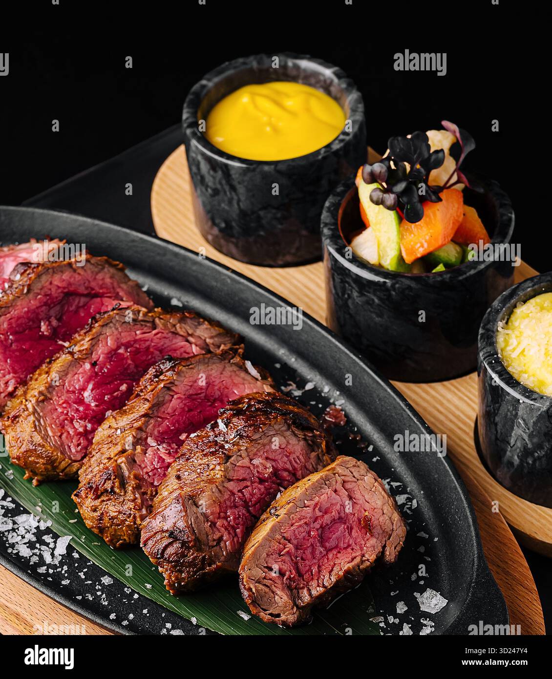 Zartes gegrilltes Steak mit lebhaften Beilagen auf einer Platte Stockfoto
