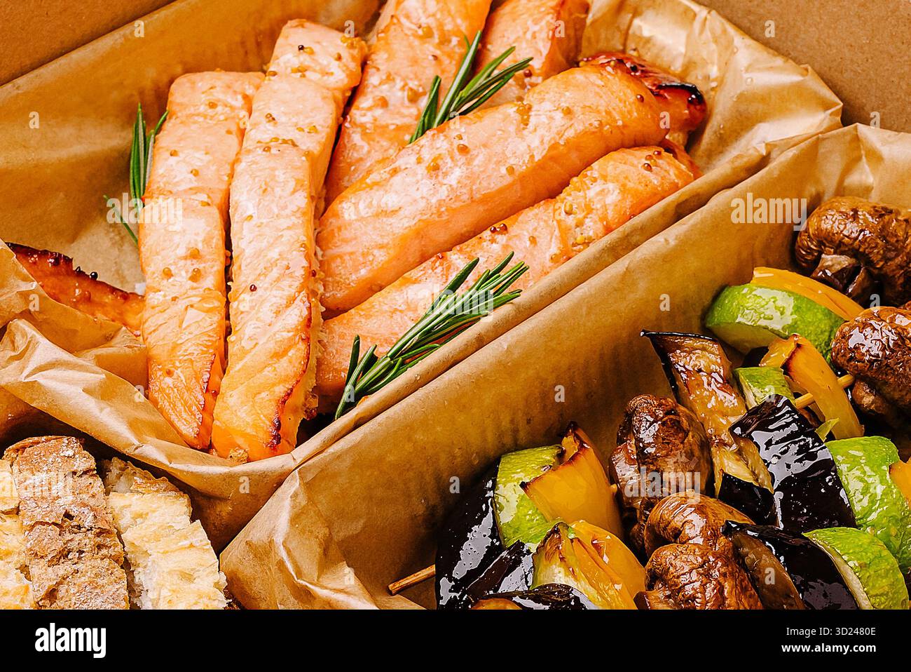 Gegrillter Lachs mit Gemüse, serviert in einem Karton bei einem Picknick Stockfoto