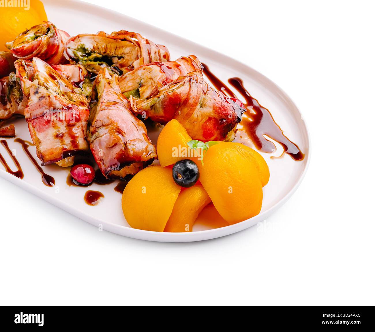 Kulinarische Kunst der mit Speck umwickelten Brötchen mit Obstgarnitur Stockfoto