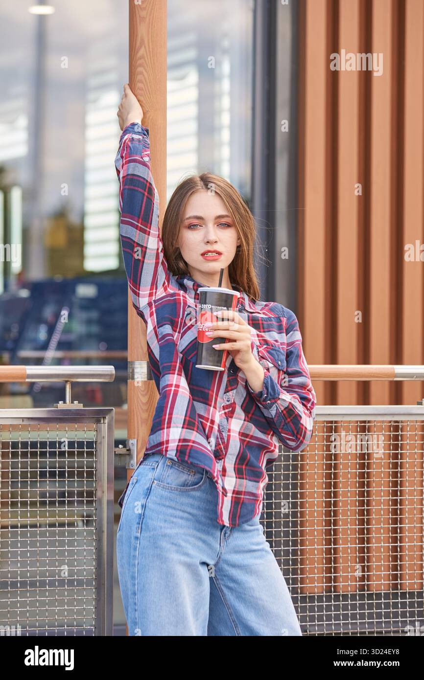 Junge kaukasische Frau genießt Kaffee im Freien in lässiger Kleidung Stockfoto