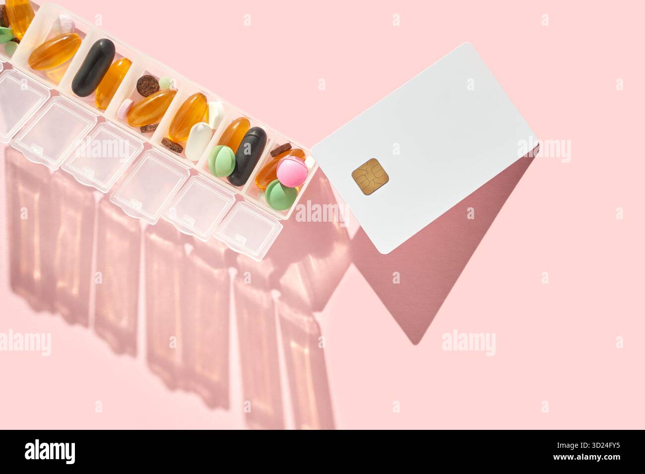 Wöchentlicher Pillen-Organisator und Karte auf rosa Hintergrund Stockfoto