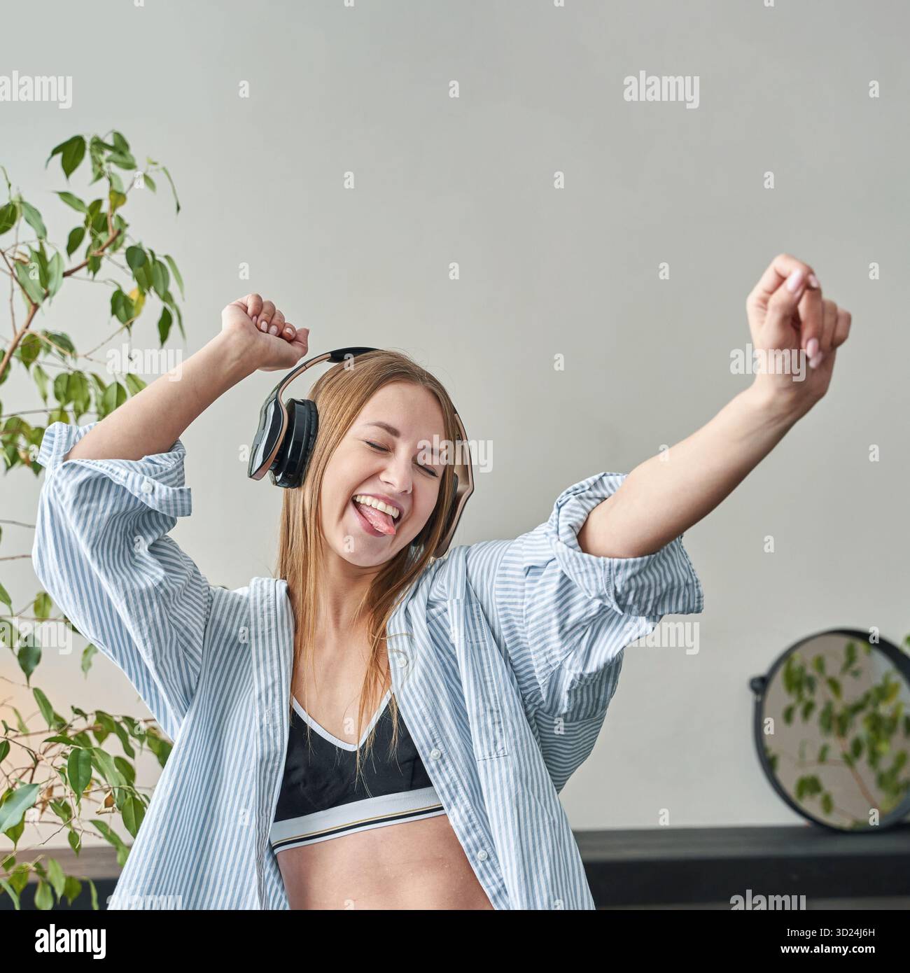 Junge kaukasische Frau, die Musik mit Kopfhörern genießt, in lässiger Kleidung tanzt Stockfoto